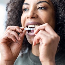 Young woman placing Invisalign in her mouth