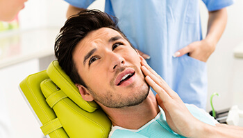 attractive man holding jaw in pain