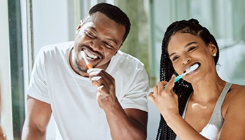 Couple brushing their teeth in front of bathroom mirror