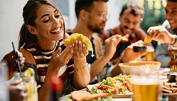 Woman eating tacos at a restaurant with friends