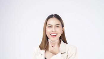 Happy woman holding Invisalign aligner in front of her mouth