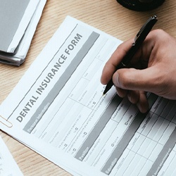 Close-up of hand filling out dental insurance form