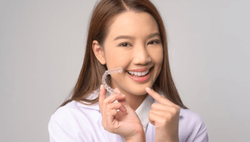 Happy woman holding clear aligner