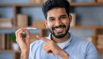 Smiling man pointing at his Invisalign aligner