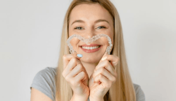 Woman holding two clear aligners in heart shape