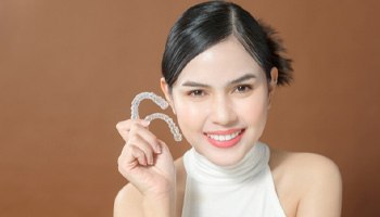 Teen girl in white shirt holding two Invisalign Teen aligners