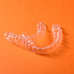 Two clear aligners arranged against orange background