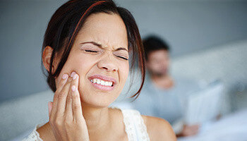 woman holding jaw in pain