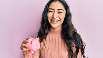 Teen girl with braces holding piggy bank