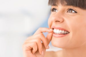 woman smiling inserting Invisalign trays