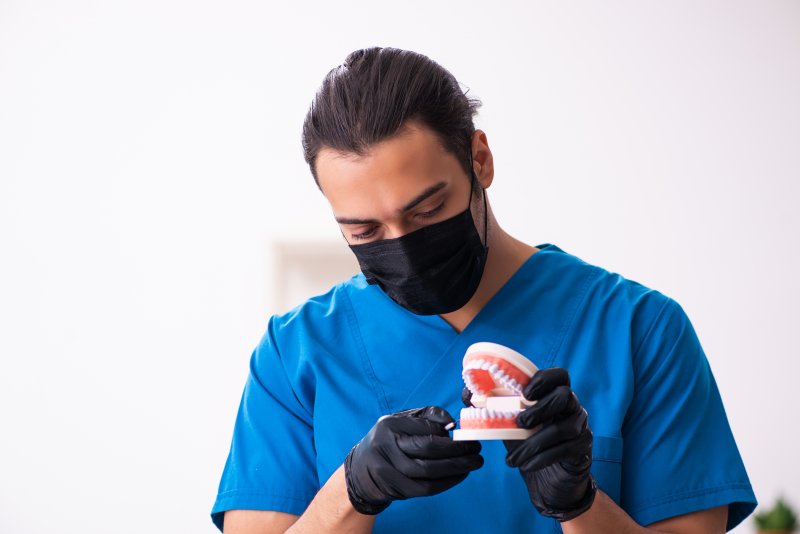 Orthodontist wearing mask and working on model teeth