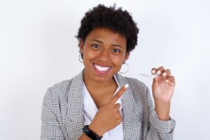 Professional woman confidently pointing at her Invisalign aligner