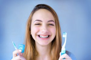 Teen girl holding tools for brushing and flossing with braces