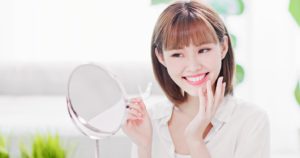 Woman holding retainer after Invisalign, smiling in mirror