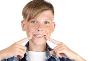 Preteen boy, smiling and pointing at his braces for children