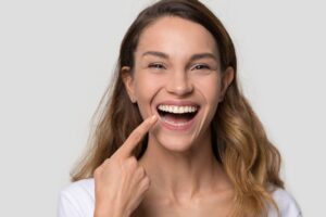Excited young woman pointing at her teeth 